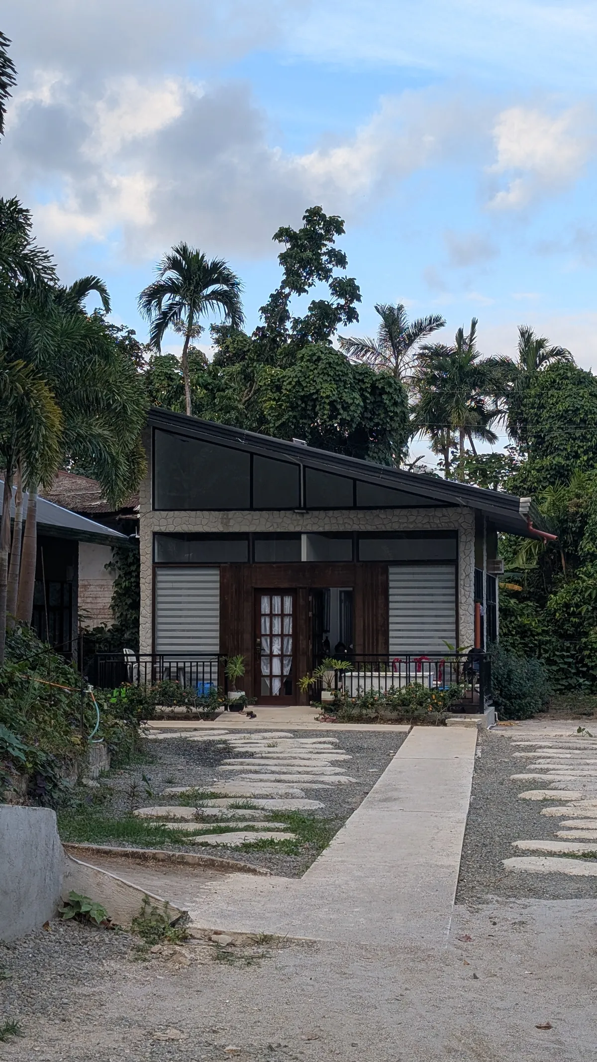 Quiet driveway approach with greenery and palms near the lodging units