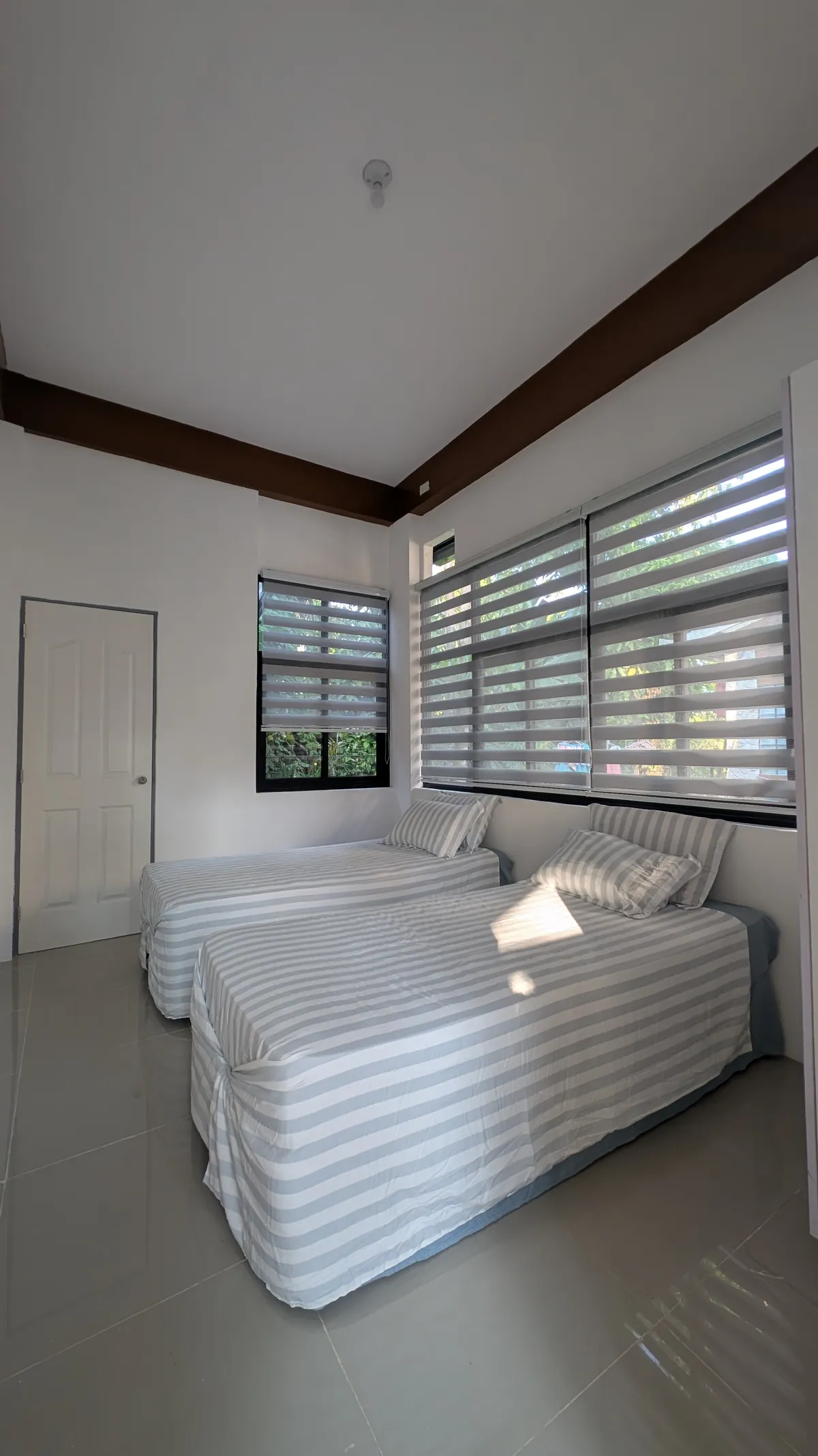 Bright twin bedroom with striped bedding and privacy blinds