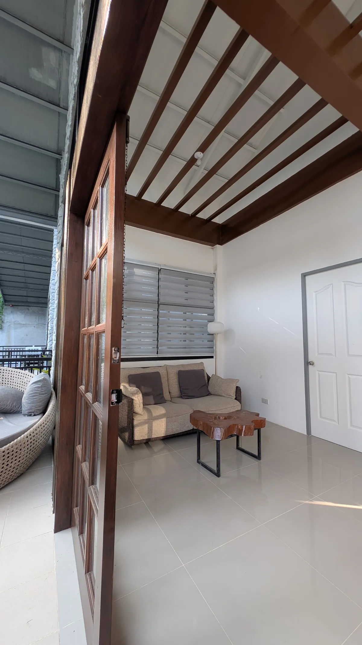 Private lounge area with sofa, table, high ceiling, and open doorway